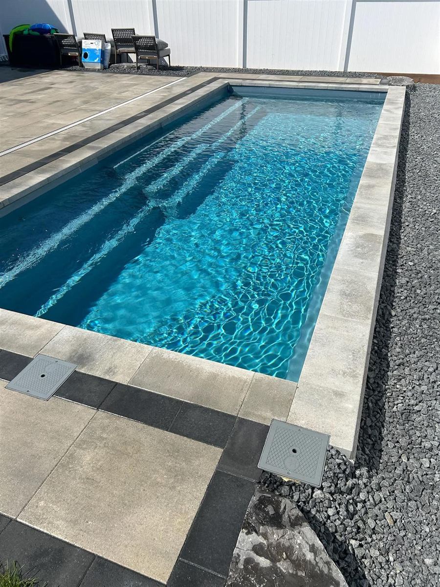 A pool with a full paver deck and coping running to the water's edge